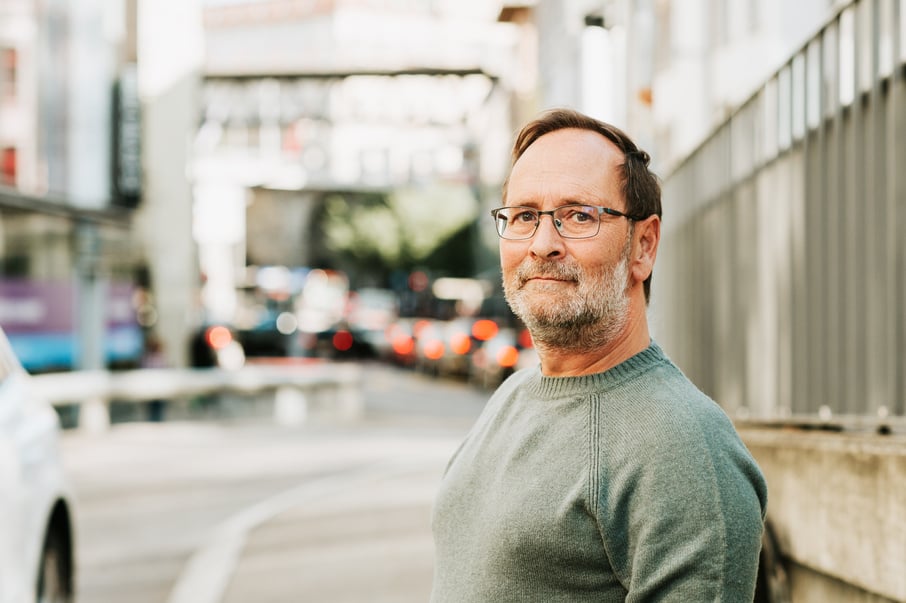 Outdoor portrait of 50 - 55 year old man wearing green pullover and eyeglasses